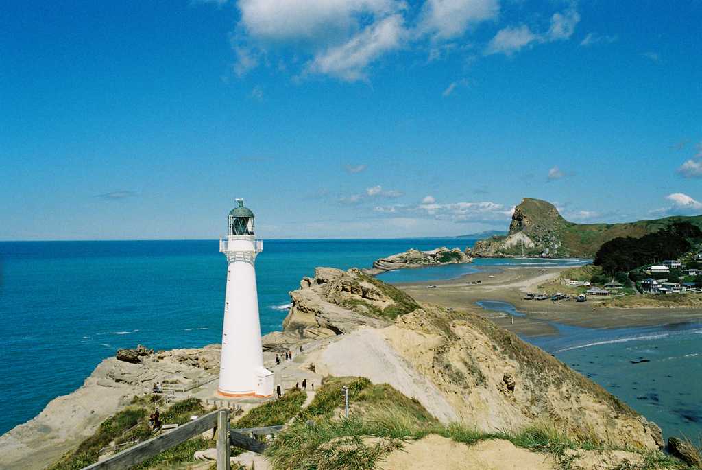 A lighthouse on a rocky outcrop surrounded by blue seas