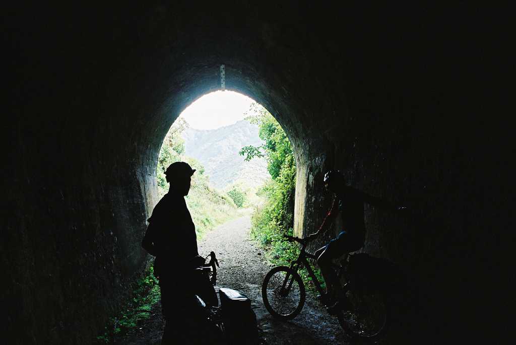A tunnel portal with two cyclists and a bright green background