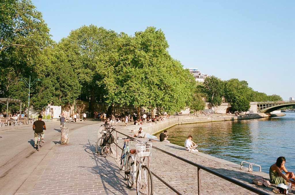 Alongside the Seine on a sunny summer's day, with people sitting on the banks and cyclists going past