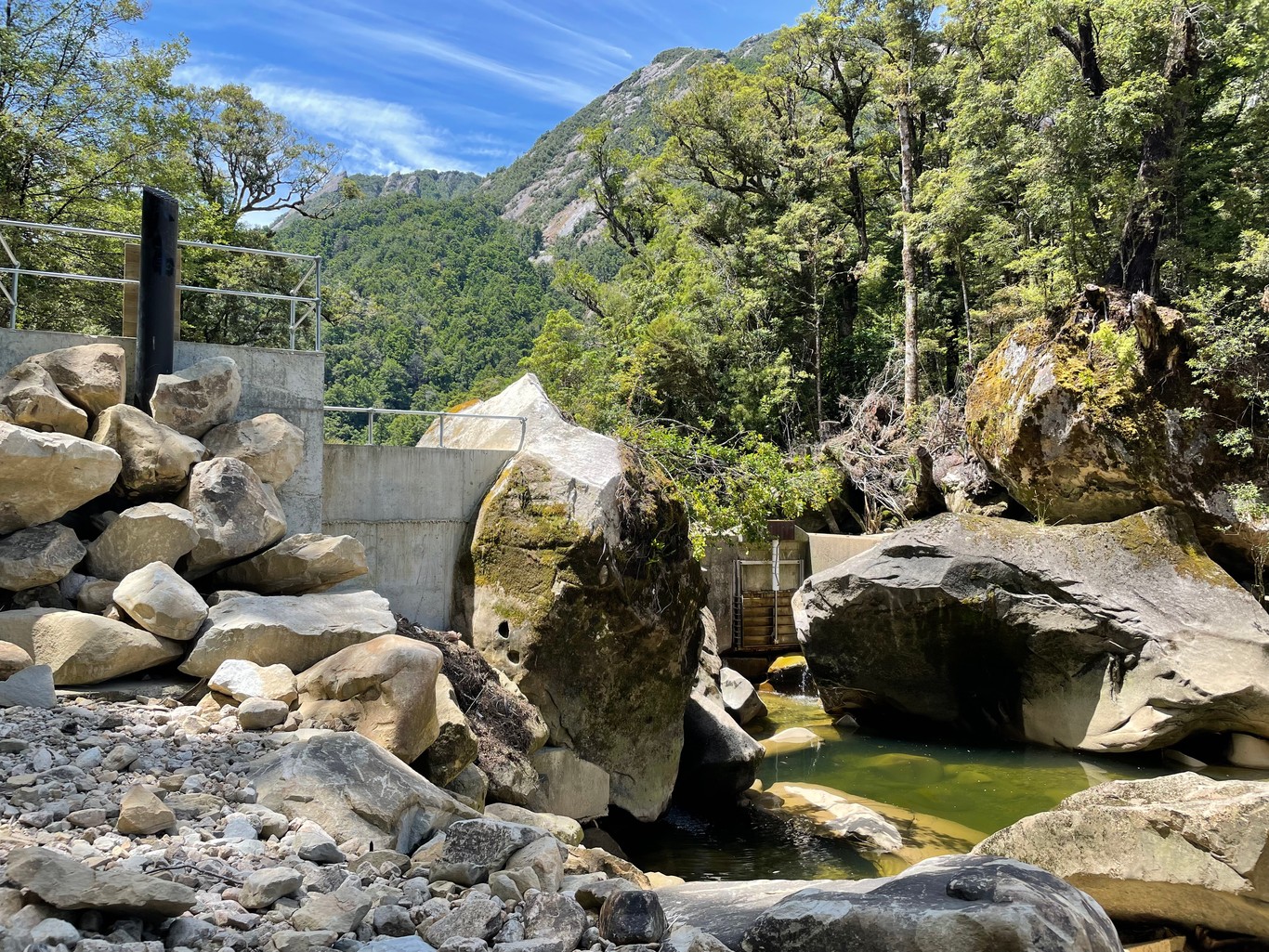 A weir with a control gate, surrounded by large boulders