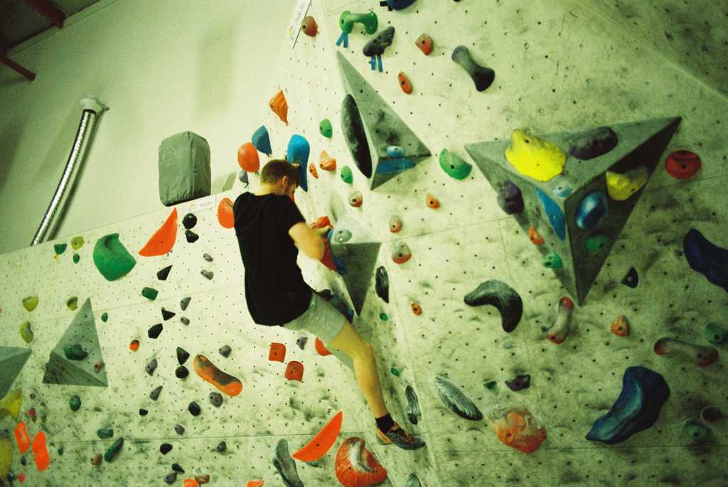 A person on an indoor climbing wall covered in brightly coloured holds