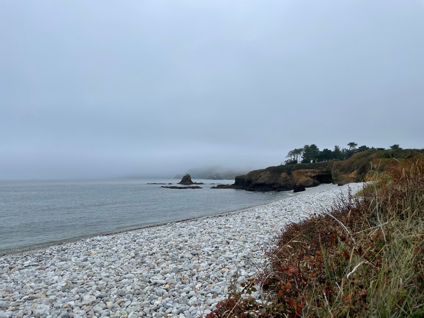 A white stone covered beach fading into a foggy background
