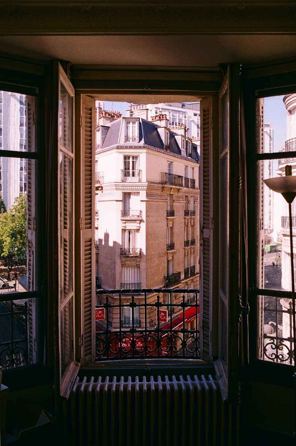 A classic French-style window framing a view of a classic Parisian multi-story stone-clad building